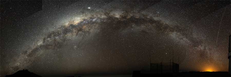 A fish-eye mosaic of the Milky Way arching at a high inclination across the night sky, shot from a dark-sky location in Chile
